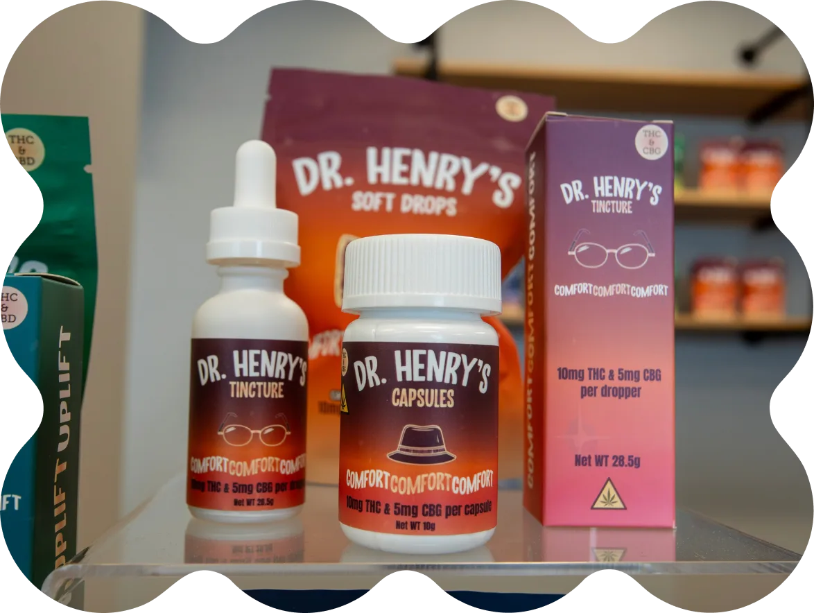 Bottles and packaging of Dr. Henrys Tincture and Capsules, and a bag of Dr. Henrys Soft Drops, displayed on a shelf.