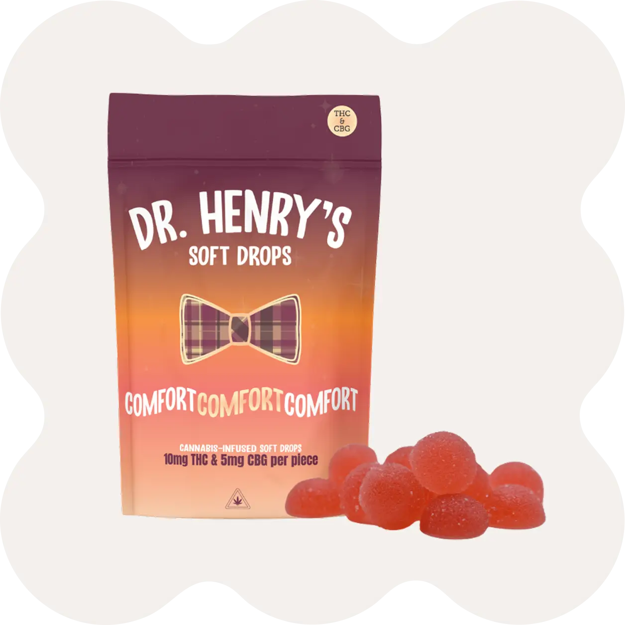 A package labeled Dr. Henrys Soft Drops stands beside a pile of red gummy candies. The packaging mentions cannabis infusion and displays Comfort Comfort Comfort.